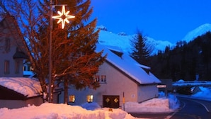 A snow-covered street at dusk with a house and a street lamp. - Jugendherberge Hospental (Hospental)