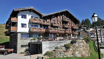 A multi-story hotel with balconies, stone facade, and a ski lift in the background.