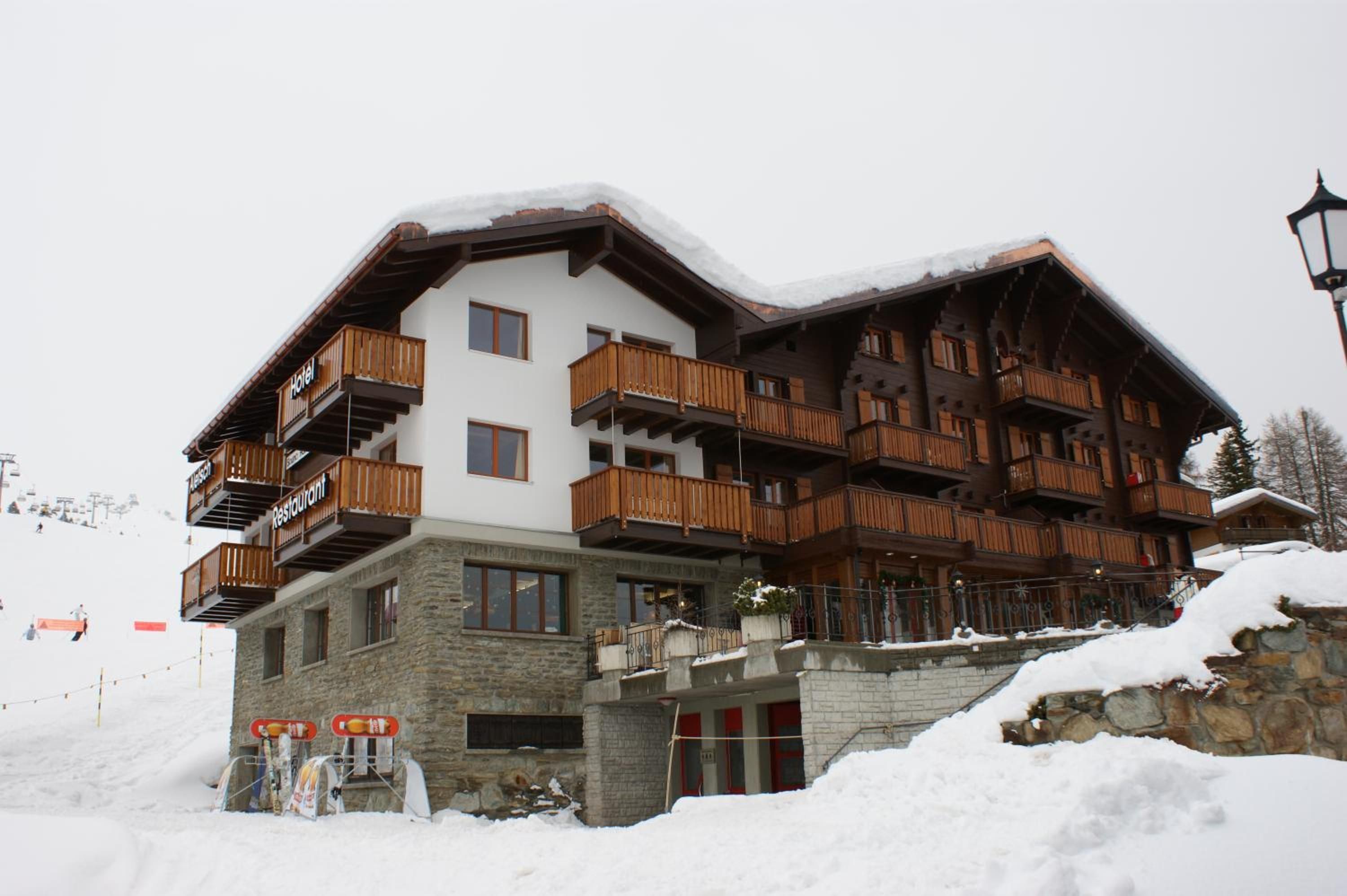 A multi-story hotel with wooden balconies and a stone facade.