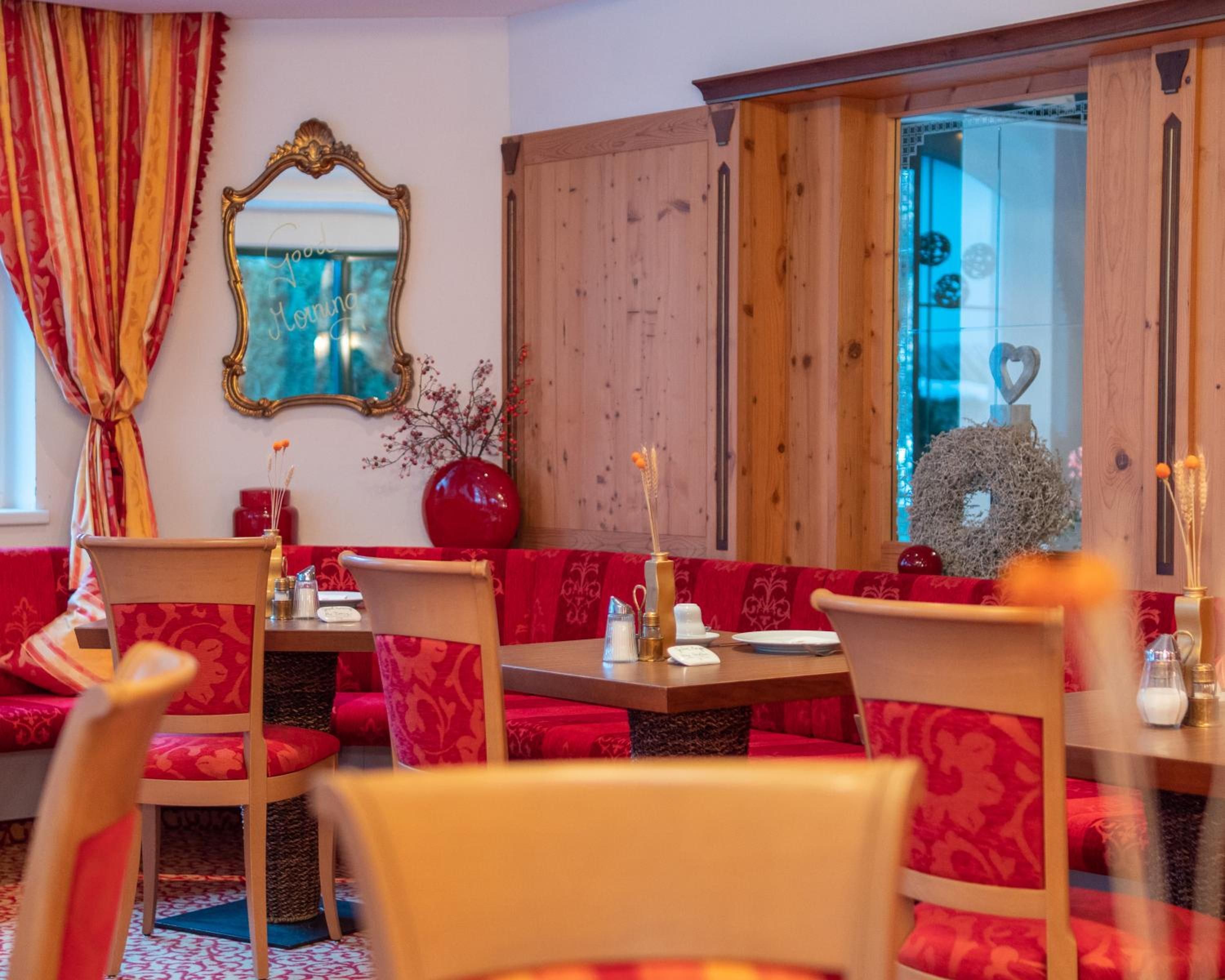 A room with red upholstered seating, a wooden cabinet, and a mirror with a decorative frame.