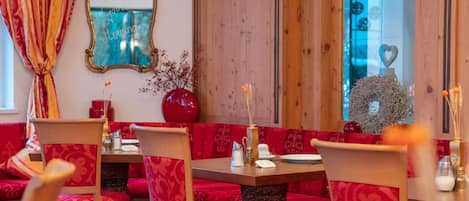Una habitación con asientos tapizados en rojo, un aparador de madera y un espejo con un marco decorativo.