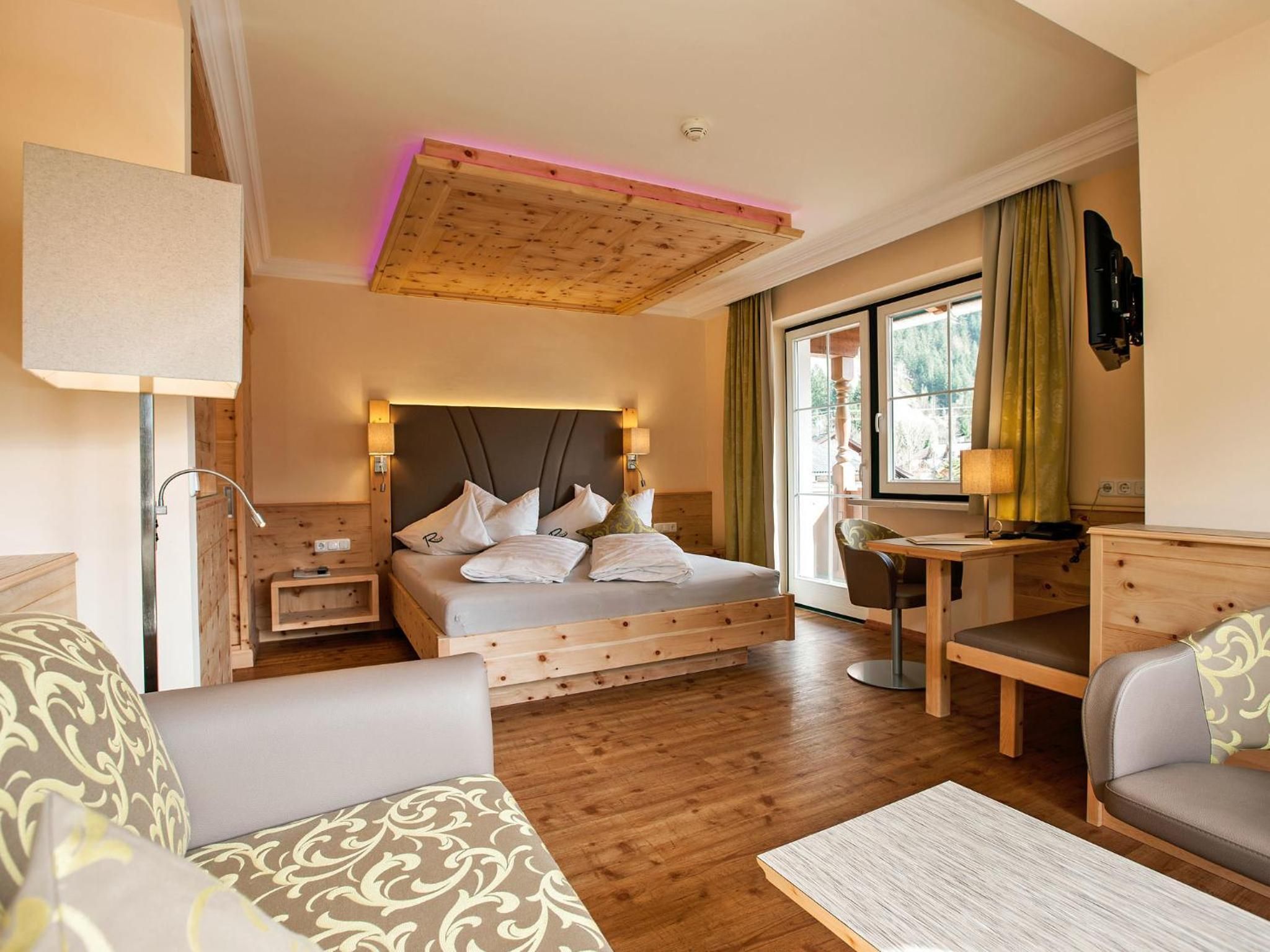 Une chambre d’hôtel avec un lit, un bureau, une chaise, un canapé et une lampe.