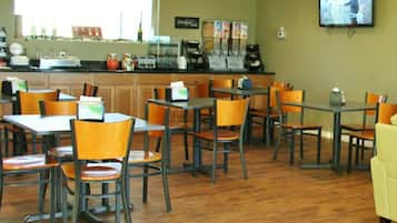A restaurant with wooden tables and chairs, a coffee bar, and a television mounted on the wall.