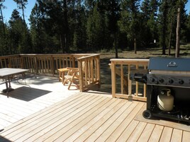 A wooden deck with a grill and seating area.