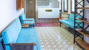 A reception area with a reception desk, multiple clocks, a blue sofa, and a patterned floor. - Hä±dä±rlä±k Konaklarä± (Safranbolu)