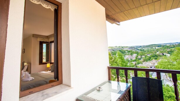 A balcony with a view of a town, a glass table, and a chair. - Hä±dä±rlä±k Konaklarä± (Safranbolu)