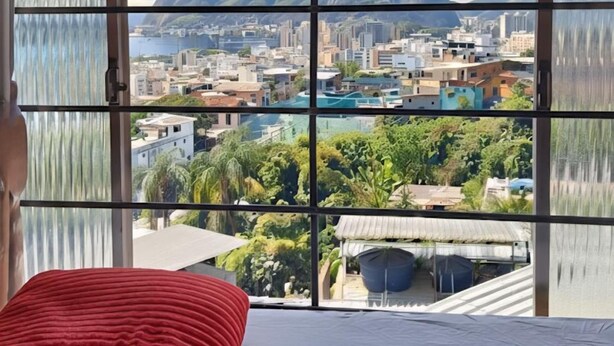 Ein Zimmer mit einem Bett und einem großen Fenster mit Blick auf Stadt und Berge.