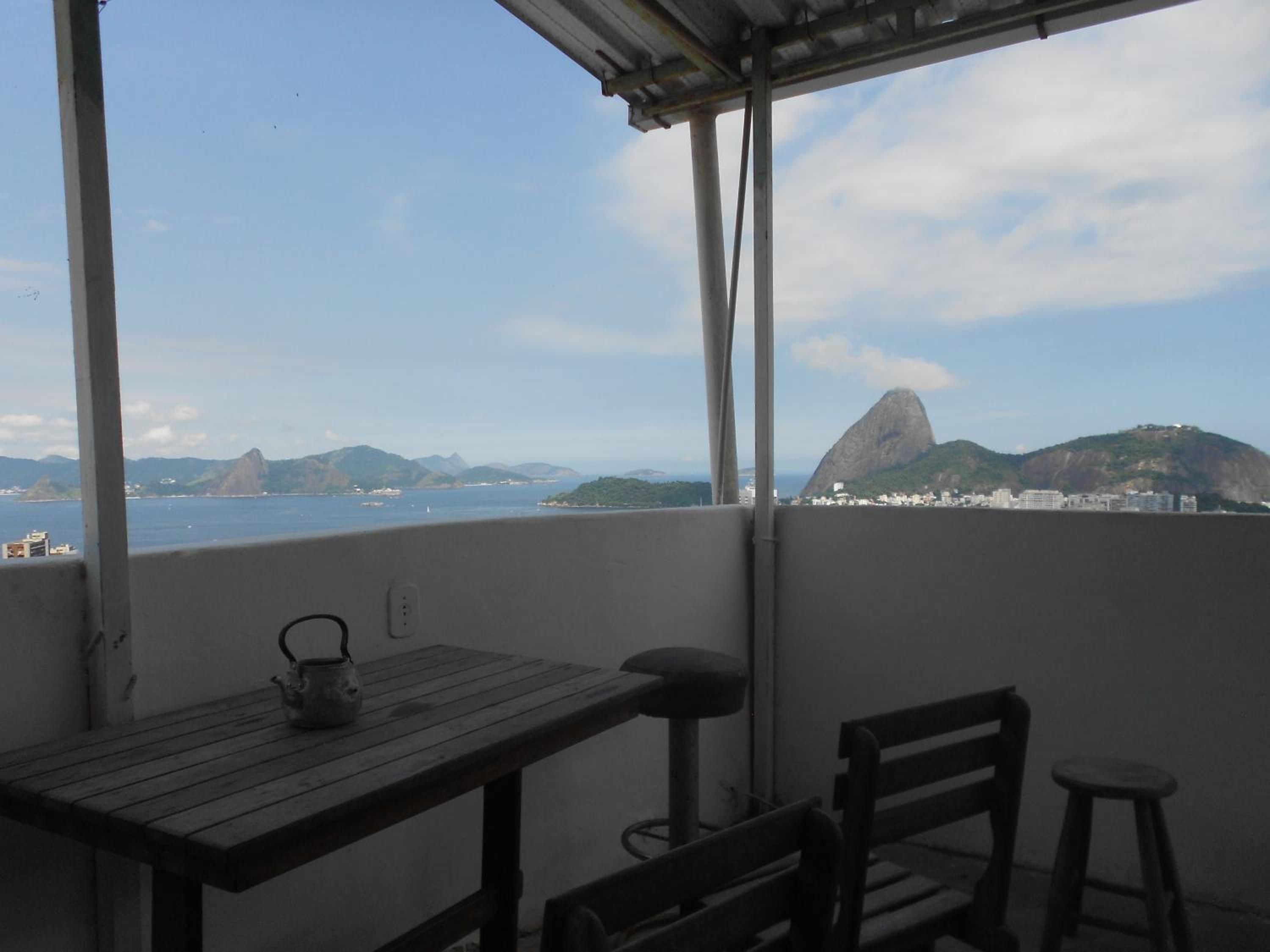 A balcony with a table, chairs, and a view of a coastal cityscape including a prominent mountain.