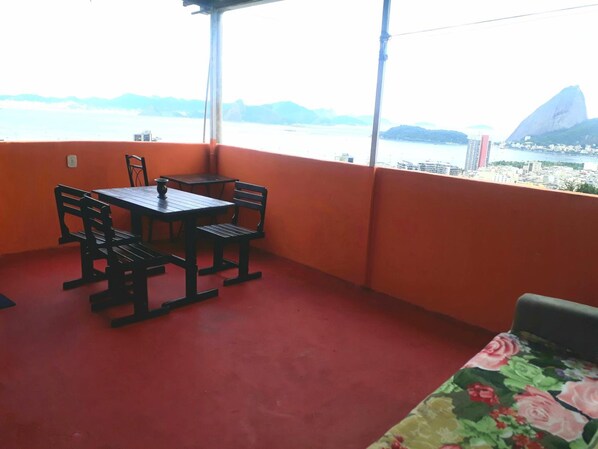 A balcony with a table and chairs, a red floor, and a view of a cityscape with a prominent mountain. - Hostel Tavares Bastos (Rio de Janeiro)