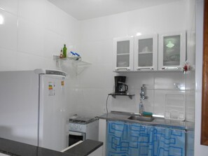 A compact kitchen with a refrigerator, stove, and a coffee maker on the countertop. - Hostel Tavares Bastos (Rio de Janeiro)