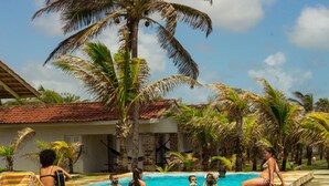 A swimming pool area with lounge chairs and palm trees. - Pousada Cabanas De Buzios (Nisia Floresta)