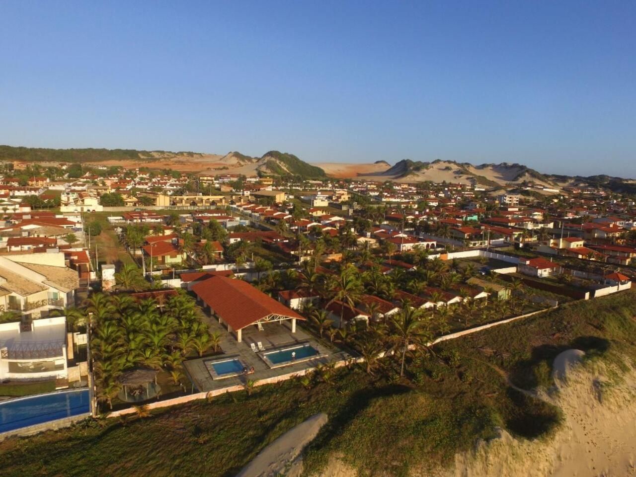 Un quartier résidentiel avec des maisons, une piscine et, au loin, un paysage vallonné.