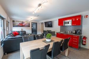 Un espacio habitable moderno con zona de comedor, cocina y un amplio ventanal con vista a la carretera.