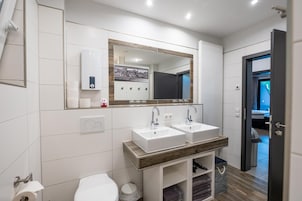Un baño moderno con dos lavamanos, inodoro y espejo.