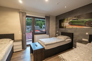 Un dormitorio moderno con una cama grande, una mesita de noche, una ventana con cortinas y un cuadro de un coche en la pared.
