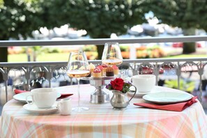 Una mesa lista para una comida, con mantel a cuadros, un jarrón de flores y un pastelero de varios niveles.