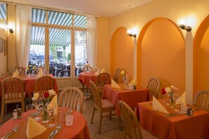 A restaurant with round tables, chairs, and a view of the street through large windows. - Al Pozz Boutique Resort (Muralto)