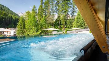 A swimming pool with a view of a mountainous landscape, surrounded by trees and buildings.