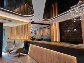 Un área de recepción moderna con un mostrador de madera, un espacio de descanso con sillas y una pared con el texto 'The Homann'.