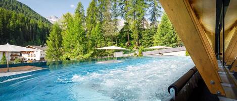 A swimming pool with a view of a mountainous landscape, surrounded by trees and buildings.