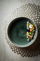A round ceramic plate with a textured green surface, placed on a decorative metal doily.