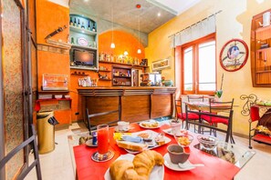 Un comedor con barra, televisor y una variedad de alimentos y bebidas sobre la mesa.