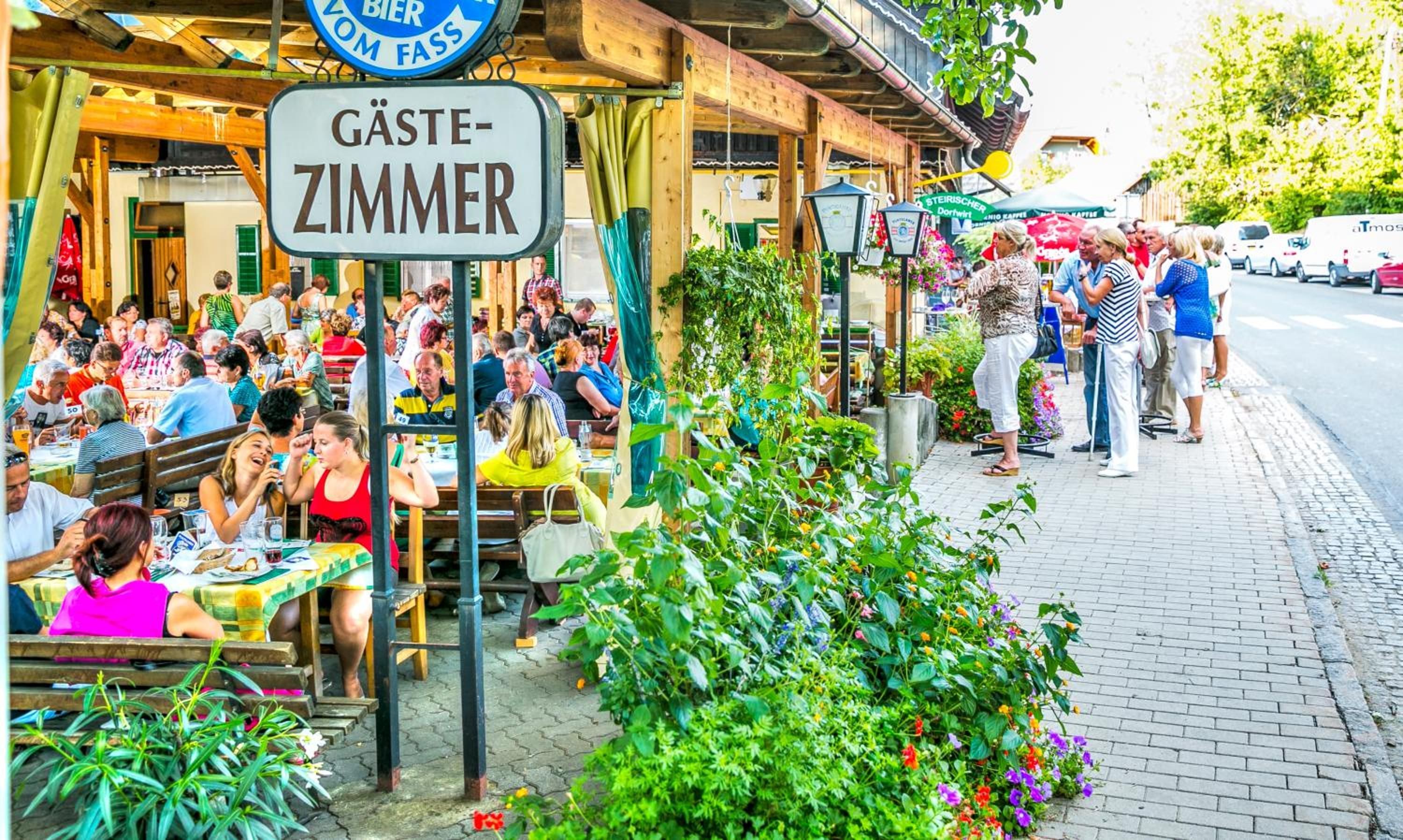 A bustling outdoor dining area with a sign indicating a 'Gästezimmer' (guest room).