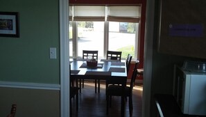 A room with a dining table and chairs, a window with a view of the outside, and a sign indicating 'COMMUNAL USE'.