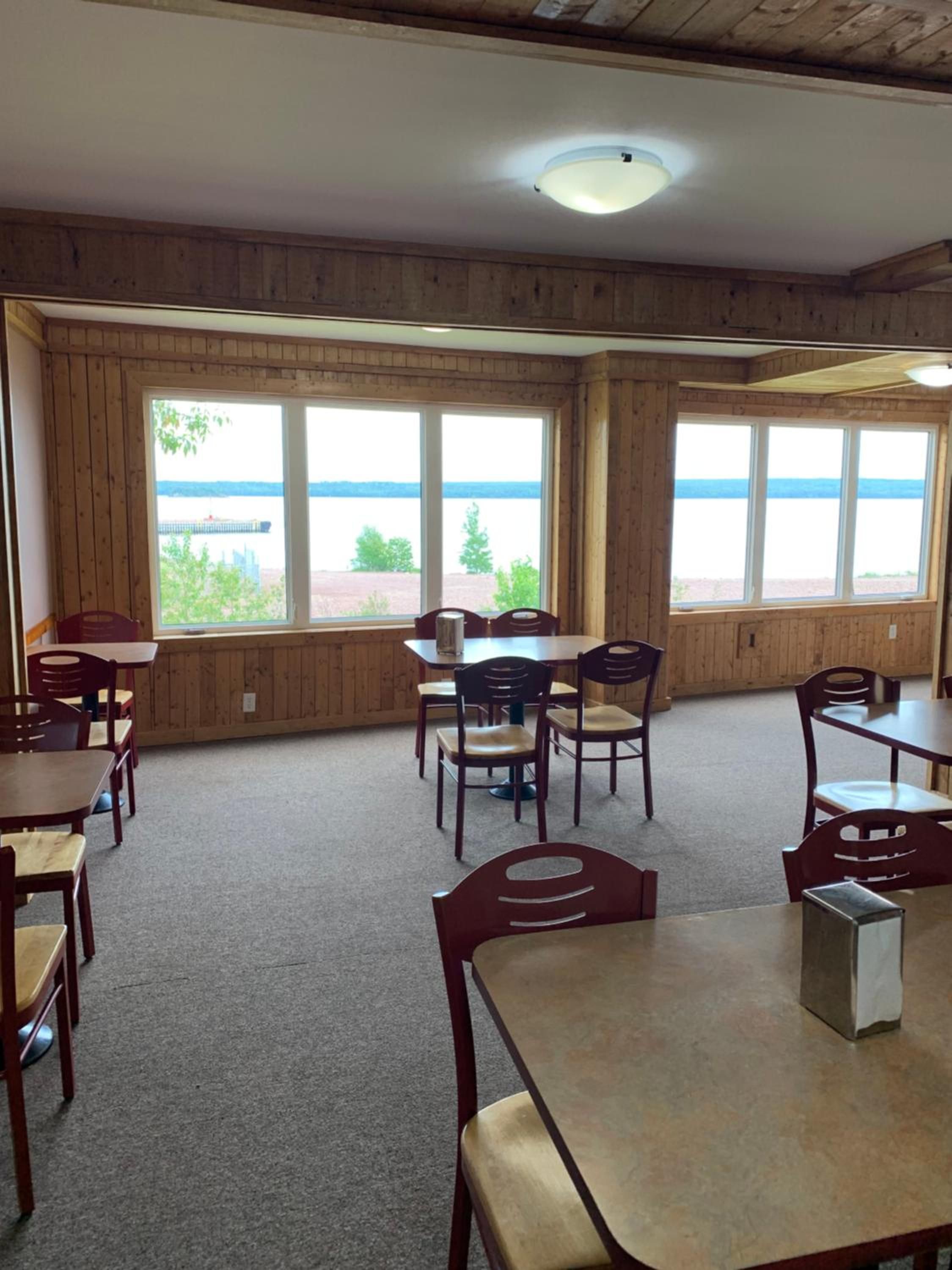 A room with wooden walls, large windows, and a table with chairs.