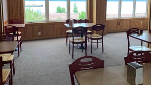 A room with wooden walls, large windows, and a table with chairs. - Exploits Inn And Suites (Botwood)