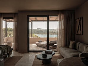 A modern living room with a sofa, a coffee table, and a view of a balcony with outdoor furniture. - OKU Bodrum (Bodrum)