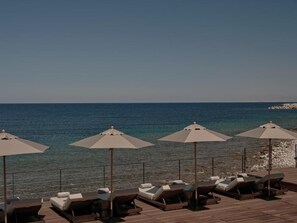 A seaside lounge area with sunbeds and umbrellas, overlooking the sea. - OKU Bodrum (Bodrum)