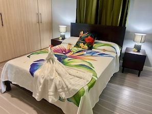 Een hotelkamer met een bed, nachtkastjes, een houten garderobe en groene gordijnen.