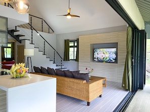 A modern living room with a staircase, a flat-screen TV mounted on a wall, and a wicker sofa. - New cozy vacation home on Bora Bora (bora bora)