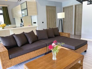 Ein modernes Wohnzimmer mit einem Ecksofa, einem Couchtisch und einer Vase mit Blumen.