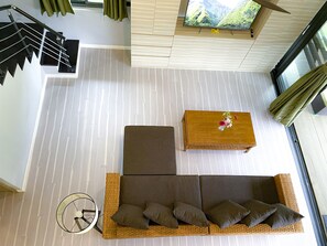 Ein zeitgemäßer Wohnraum mit Treppe, einer Sofagarnitur, einem Couchtisch und einem Fernseher.
