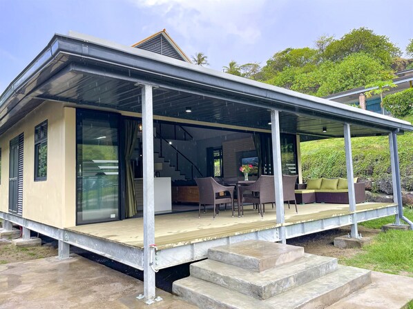 Een modern huis met een overdekte veranda, een trap die naar de ingang leidt en uitzicht op de omliggende groen.