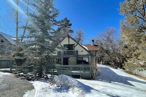 A two-story house with a balcony, surrounded by snow-covered ground and trees. - 5 Kern's Cabin (Big Bear Lake)