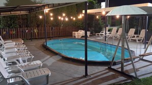 Ein Pool mit Liegestühlen und Lichterketten.