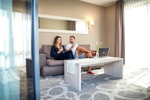 A hotel room with a sofa, a coffee table, and a laptop. - Hotel Rondo (Wabrzezno)