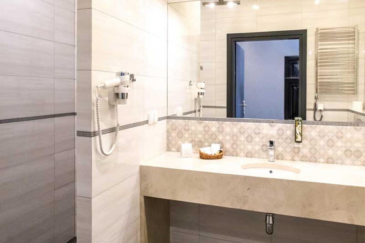 A bathroom with a large mirror, a sink, and a shower area.