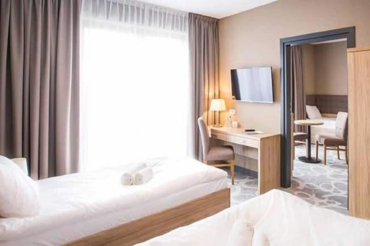 A hotel room with a bed, desk, chair, and wardrobe.