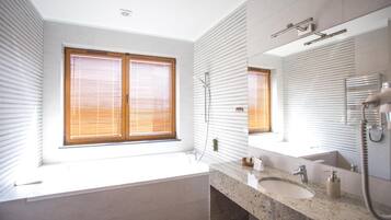 A modern bathroom with a large window, a bathtub, a sink, and a shower.