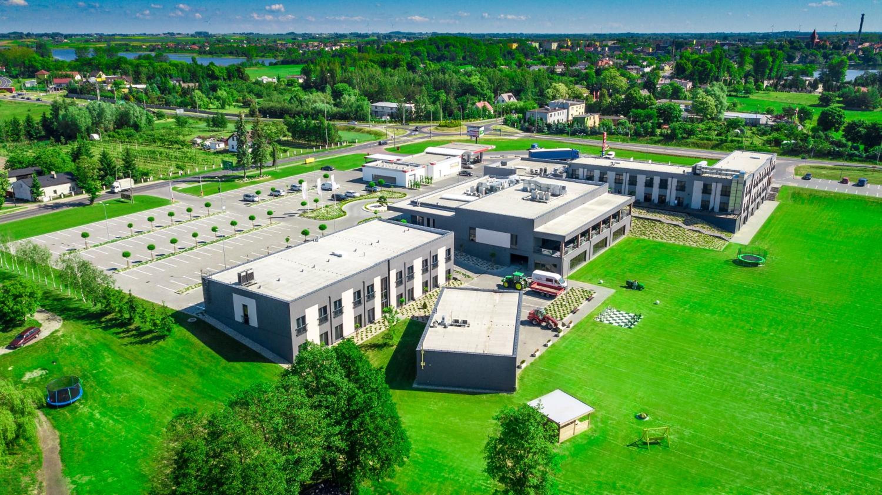 A large industrial building complex with multiple parking lots and green spaces.