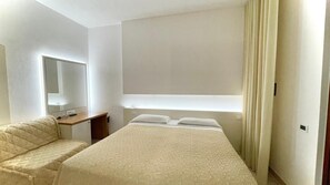 A hotel room with a bed, a desk, a mirror, and a window with curtains. - Hotel Boschetto (Follonica)