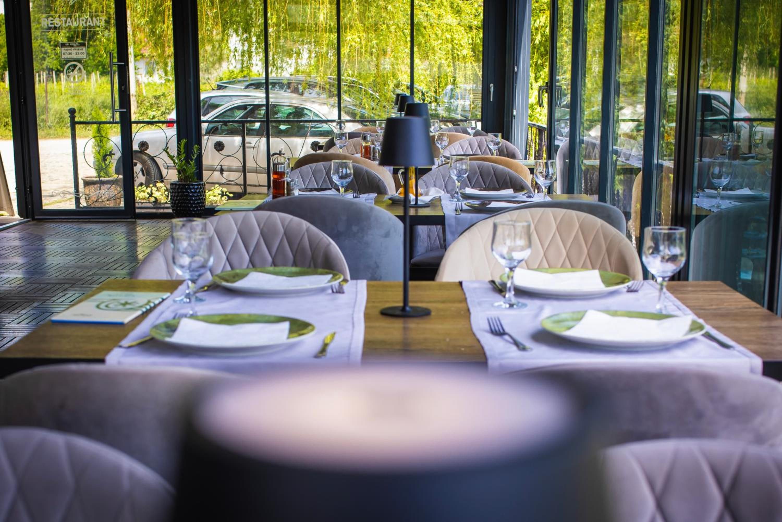 Ein Restaurant mit gedeckten Tischen, Blick auf parkende Autos vor der Fassade und einem Schild mit den Parkstunden.