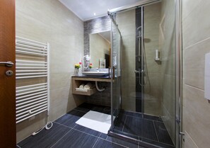 Un baño moderno con cabina de ducha de vidrio, un lavabo blanco y un perchero para toallas.