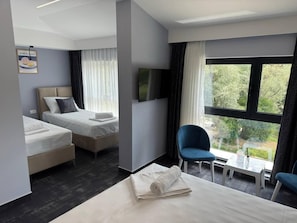 Habitación de hotel con dos camas, televisión, una mesita y una silla.