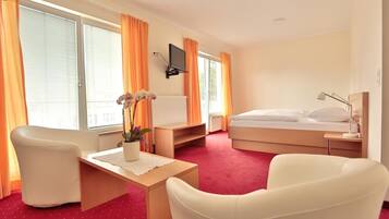 A hotel room with a bed, a desk, a chair, a TV, and a window with curtains.