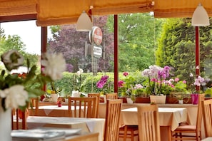 An outdoor dining area with tables and chairs, surrounded by potted plants and flowers. - Hotel Reineldis (Mureck)